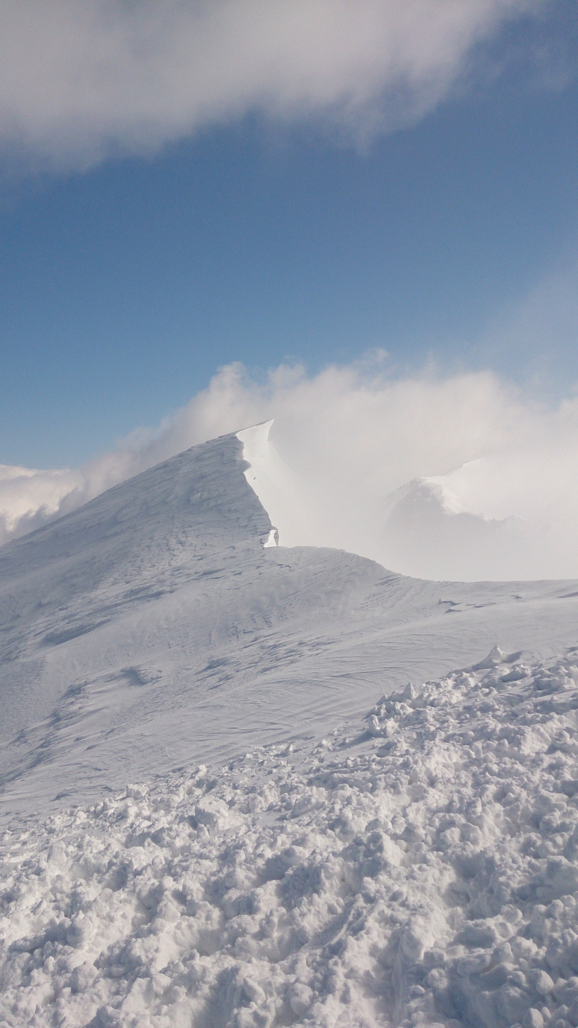 大山頂上から稜線を見る、ガスが吹き上げる稜線上には雪庇も見える