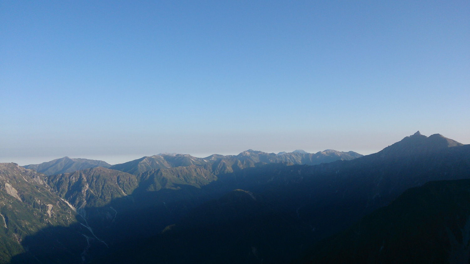 西穂高からみる槍ヶ岳―黒部五郎の稜線、まだ早朝で穂高稜線の日陰が下部に残る
